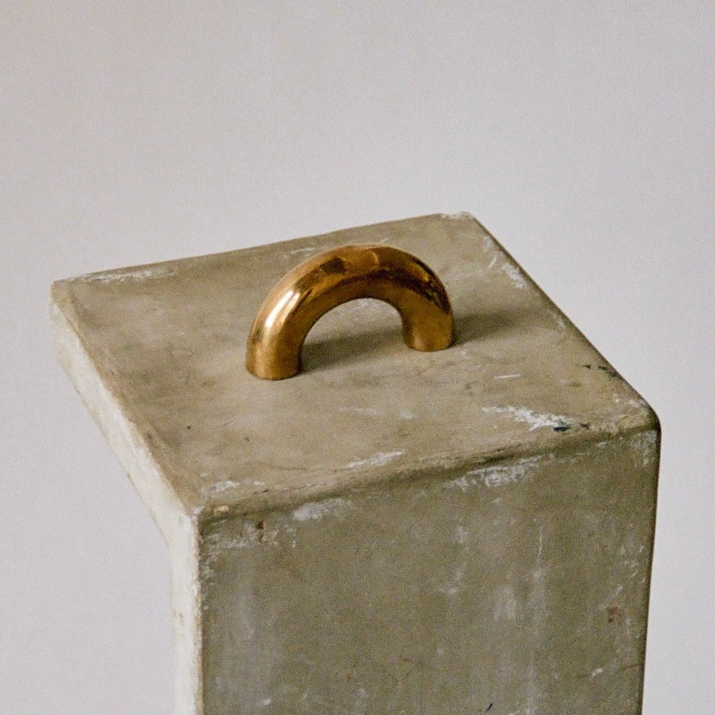 Polished brass Maha Alavi Cercle thick pull on a concrete plinth.