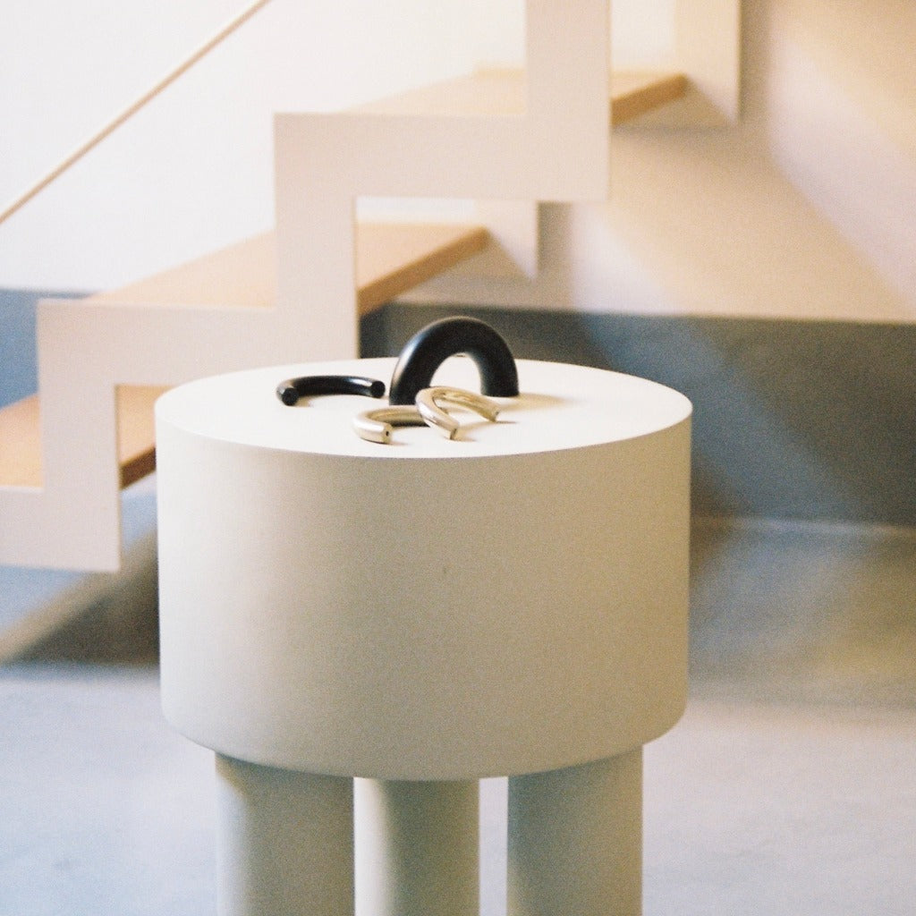 Matte black Maha Alavi Cercle thick pull on a white cylinder table.