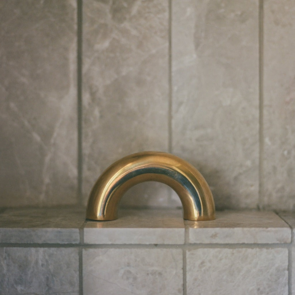 Brass Maha Alavi Cercle thick pull on a stone-tiled wall.