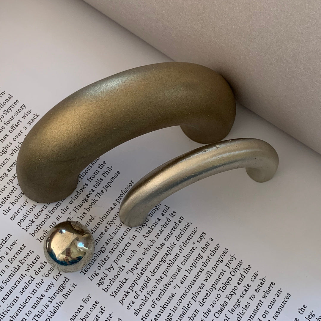 solid cast natural and white brass and bronze curved cabinet hardware handle by Maha Alavi