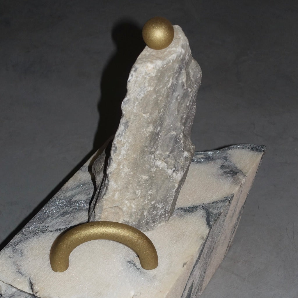 Brass Maha Alavi Cercle thin long pull styled on a rock.