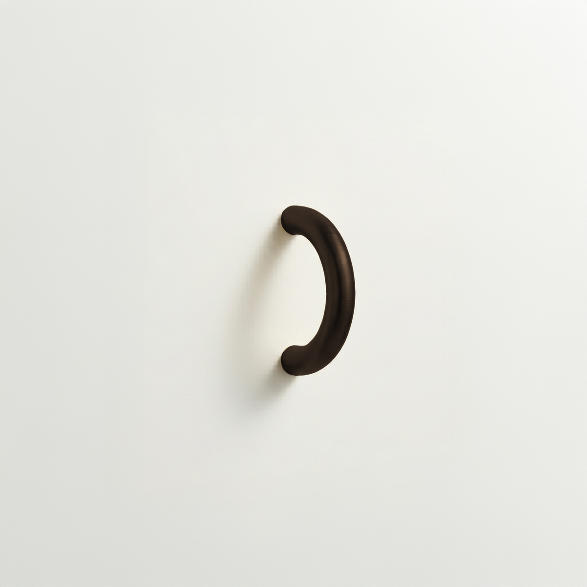 Oxidized bronze Charlie Arc pull, a small half-round arc handle, mounted on a white surface.
