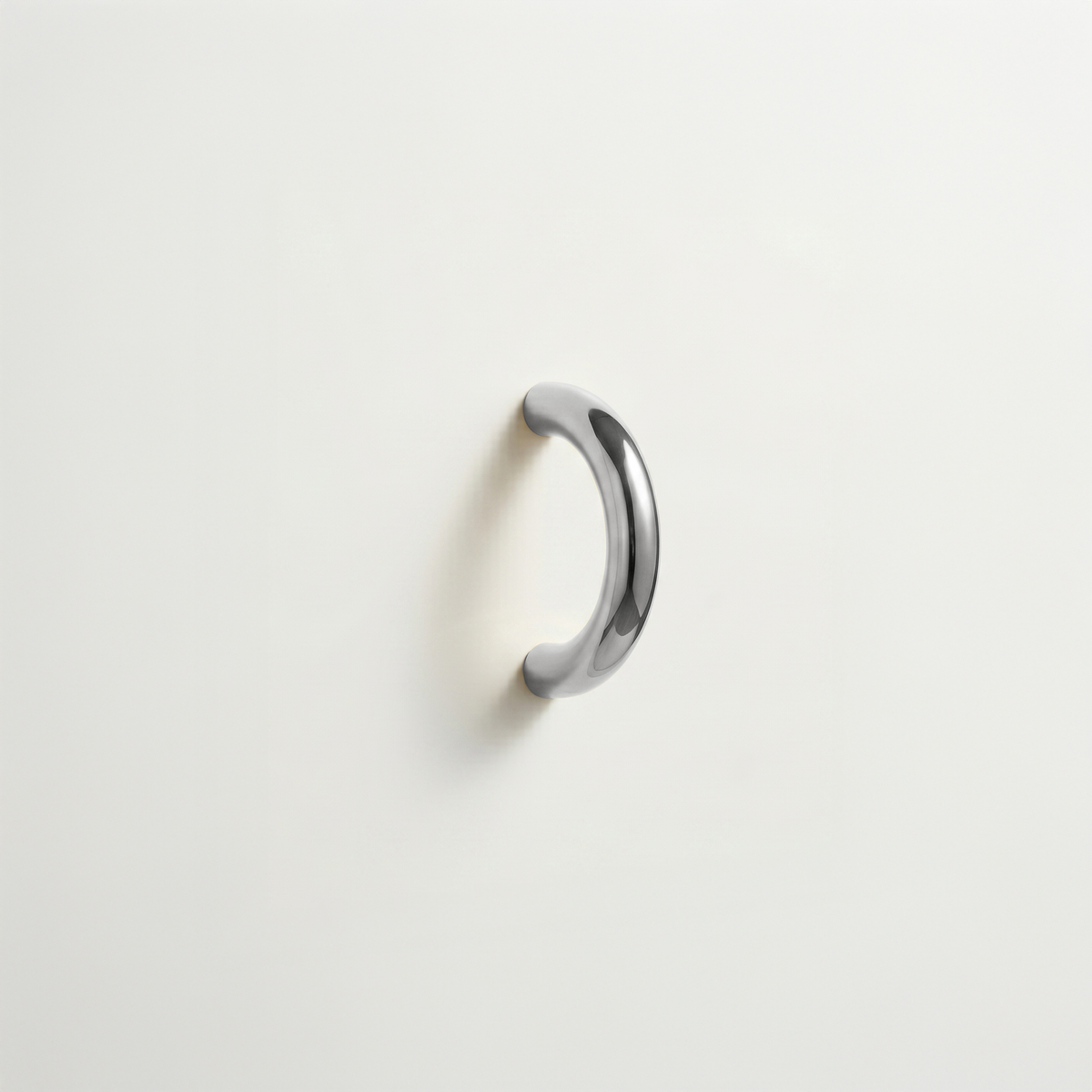 Polished chrome Charlie Arc pull, a small half-round arc handle, mounted on a white surface.