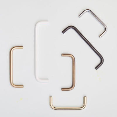 A variety of Charlie Bar Pull Handles in different sizes and finishes placed haphazardly.