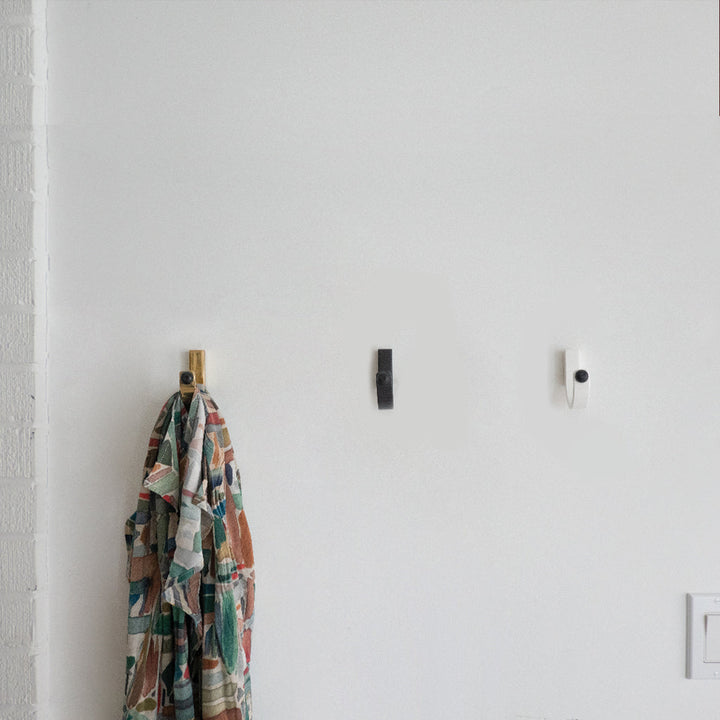 A CBH Charlie Bumper Hook hanging on a wall next to a light switch.