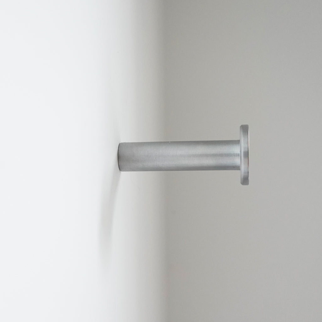A close up of a CBH Charlie Nail Hook on a white wall.