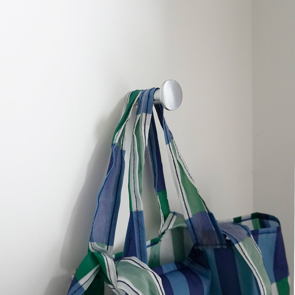 A CBH Charlie Nail Hook in blue and green stripes hanging on a wall.