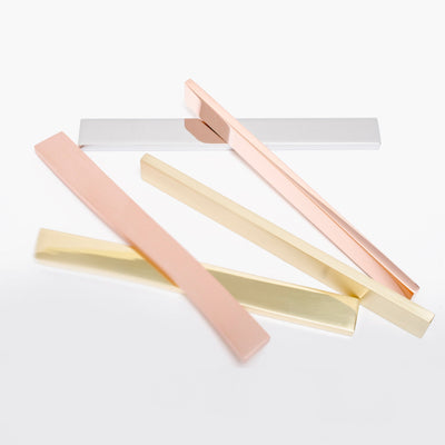Three different colors of Baccman Berglund Clean Cut Pull toothbrushes on a white surface.