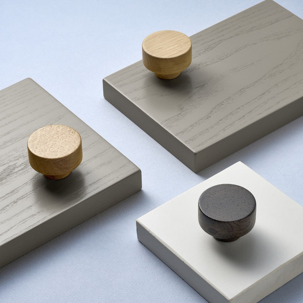 Furnipart Row cabinet knobs in Clear Lacquered, Nordic Oak, and Dark Brown oak, shown on painted sample boards.