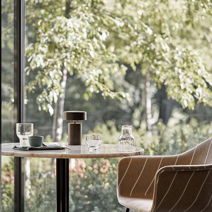 An Audo Column LED Table Lamp sitting at a table near a window.