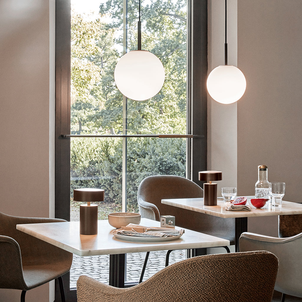 An Audo Column LED Table Lamp on a table with a plate of food on it in front of a window.