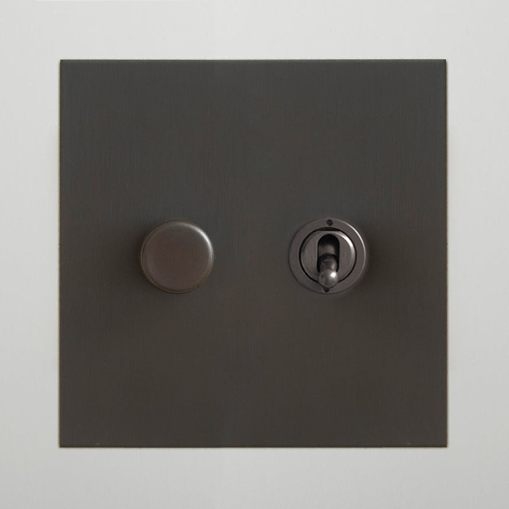 Antique bronze Forbes & Lomax switch plate with a rotary dimmer and a toggle switch.
