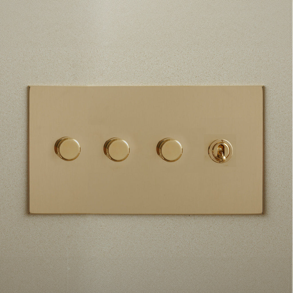 Brass Forbes & Lomax switch plate with three dimmers and a toggle.