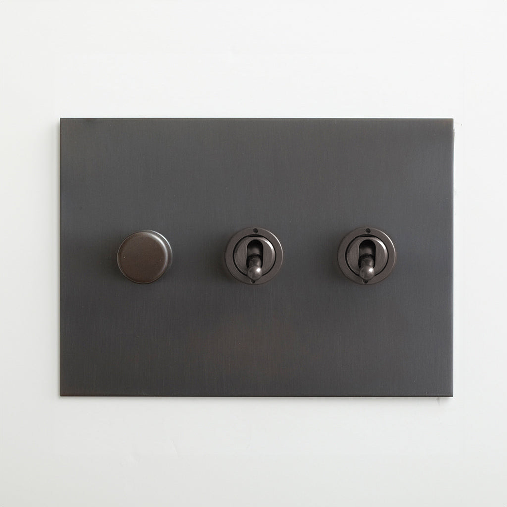 Antique bronze Forbes & Lomax switch plate with a dimmer and two toggles.