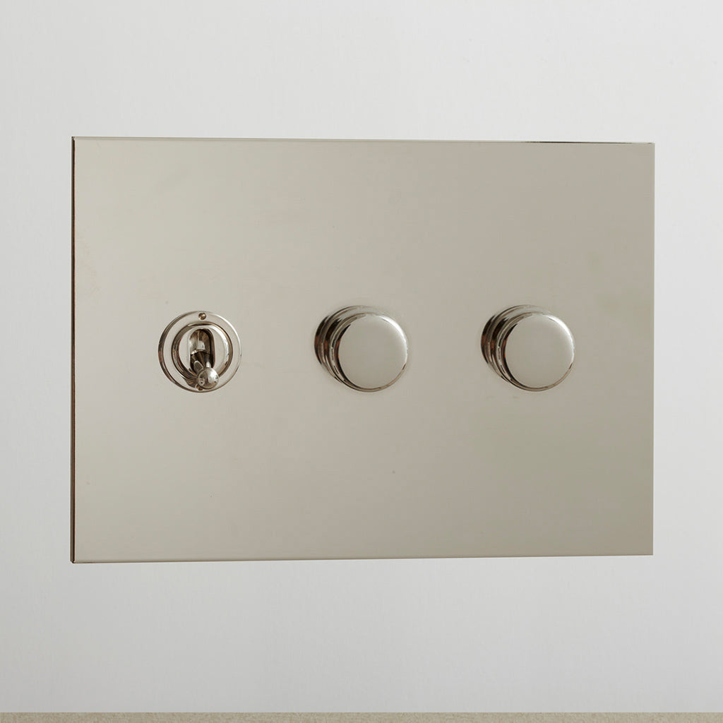 Nickel Forbes & Lomax switch plate with a toggle and two dimmers.