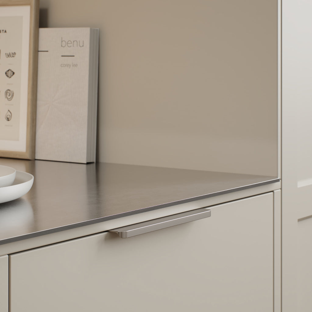 Matte inox look Furnipart Comet edge pulls, 160 mm, on beige drawer fronts under a stainless countertop.