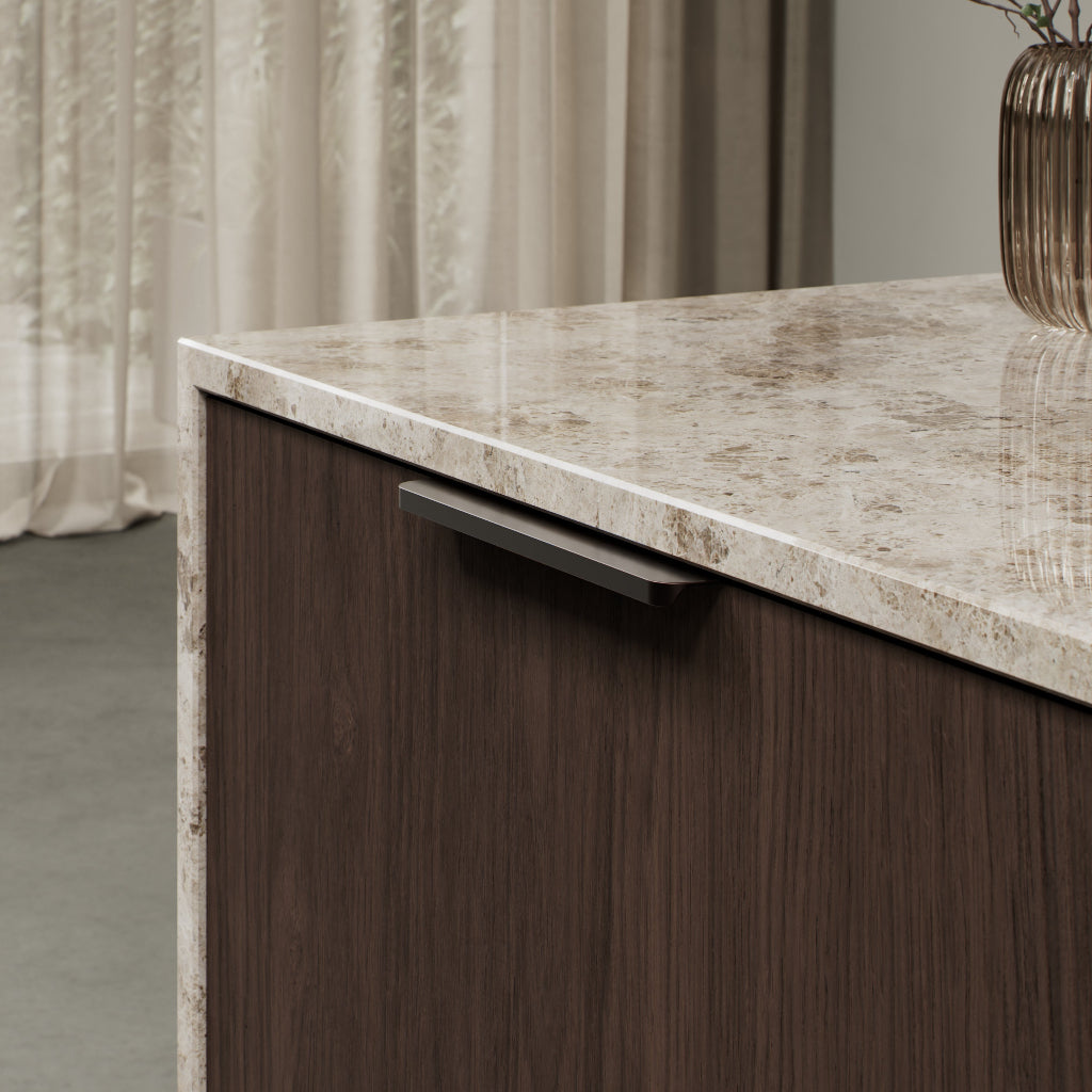 Matte bronze Furnipart Comet edge pull, 160 mm, on a walnut cabinet door under a marble countertop.