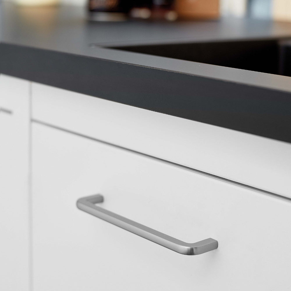 Inox look Furnipart Compact cabinet handle, 160 mm, on a white drawer under a black countertop.