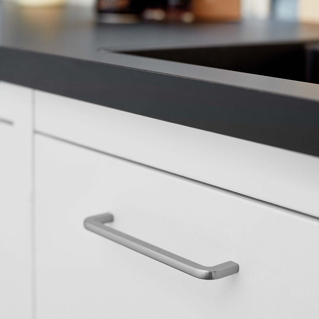 Inox look Furnipart Compact cabinet handle, 160 mm, on a white drawer under a black countertop.