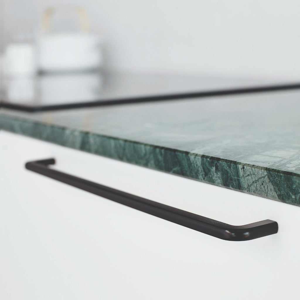 Matte black Furnipart Compact cabinet handle, 320 mm, on a white drawer under a green marble countertop.
