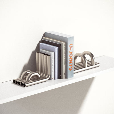stainless steel TUBE Bookends photographed on a white shelf with a collection of books in between on a white background