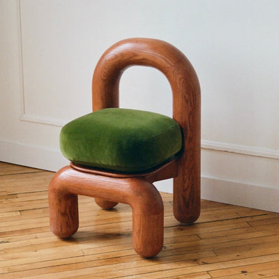 lithic dining chair with red oak frame and green velvet upholstery seat on wooden floor