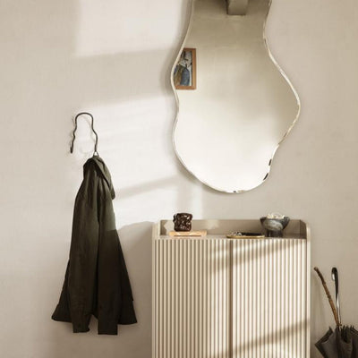A Ferm Living Curvature Double Hook mirror and coat rack in a room.