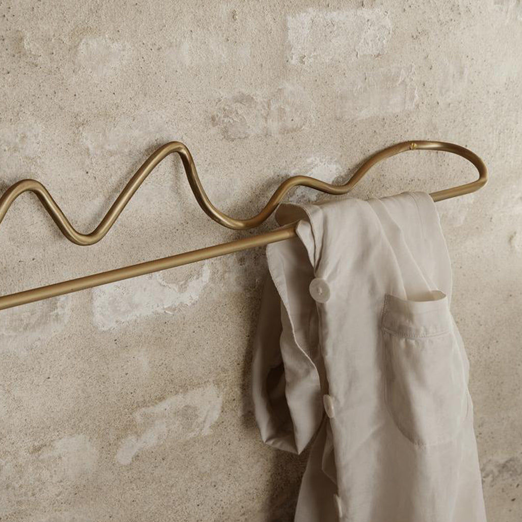 A Curvature Towel Bar by Ferm Living with a white shirt hanging on it.