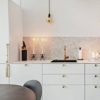 Brass Curve knobs and handles installed in a modern white kitchen. 