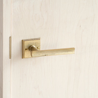 A close up of a MATUREWARE Curved Lever on a wooden door.