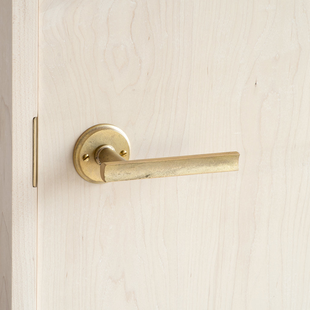 A close up of a MATUREWARE Curved Lever on a wooden door.