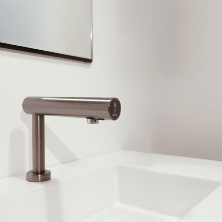 Bathroom sink with a modern deck mounted Dan Dryer stainless steel faucet in a minimalistic setting