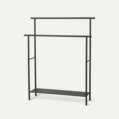 A black Dora Towel Stand with a shelf underneath it by Ferm Living.
