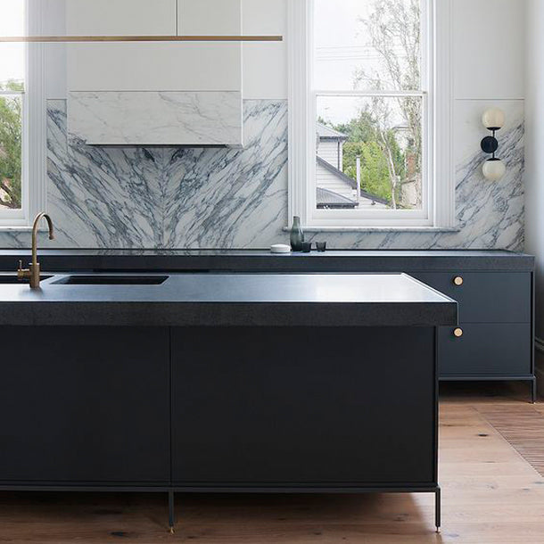 a kitchen with a Dot Knob from Baccman Berglund on the marble counter top and black cabinets.