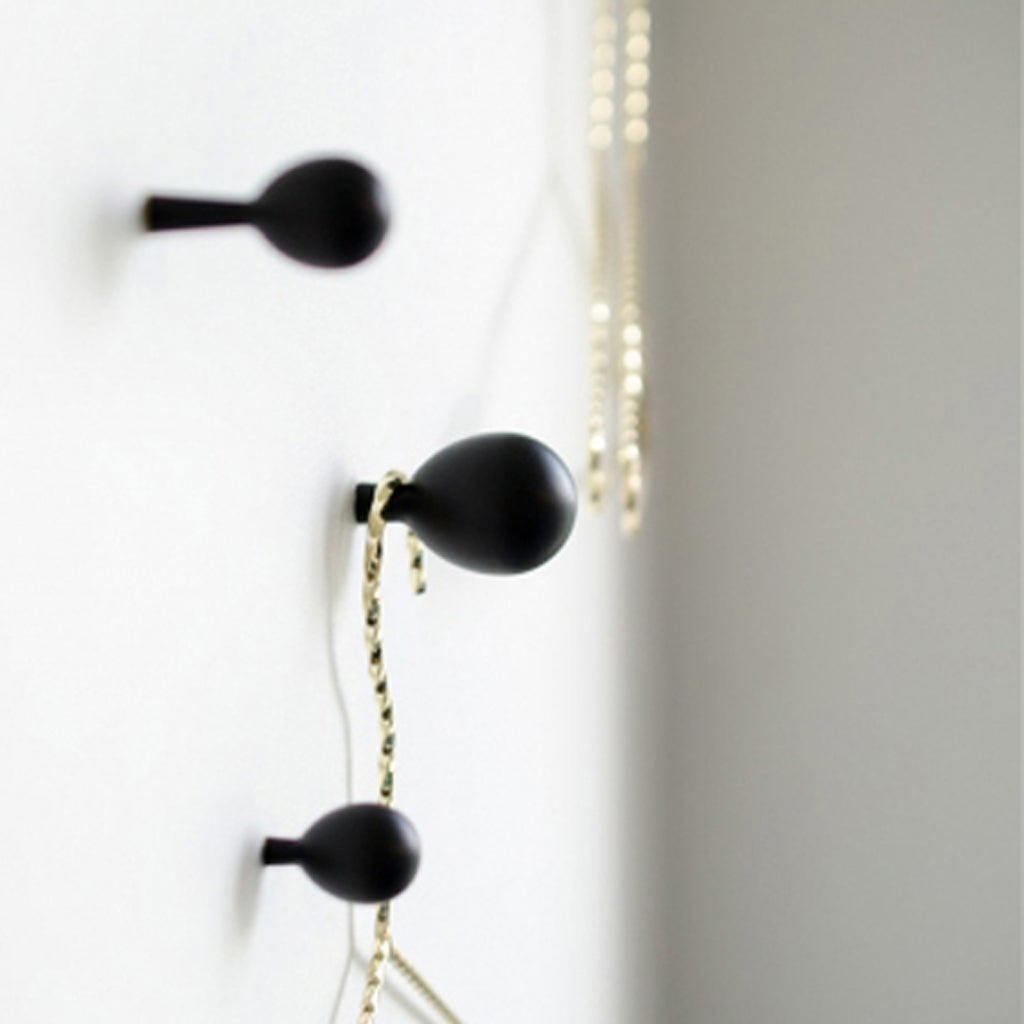 A pair of Baccman Berglund Drop Hook ear buds hanging from a wall.