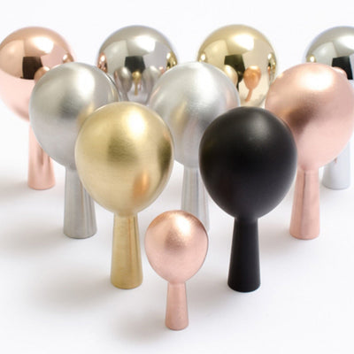 A group of metallic and black Baccman Berglund Drop Hook knobs on a white surface.