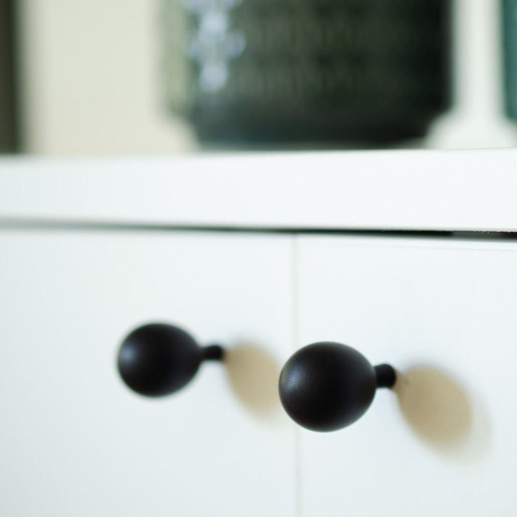A close up of a white cabinet with Baccman Berglund Drop Knobs.