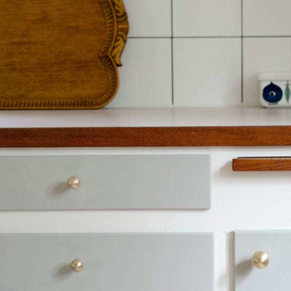 A close up of a Baccman Berglund Drop Knob on a drawer with a mirror in the background.