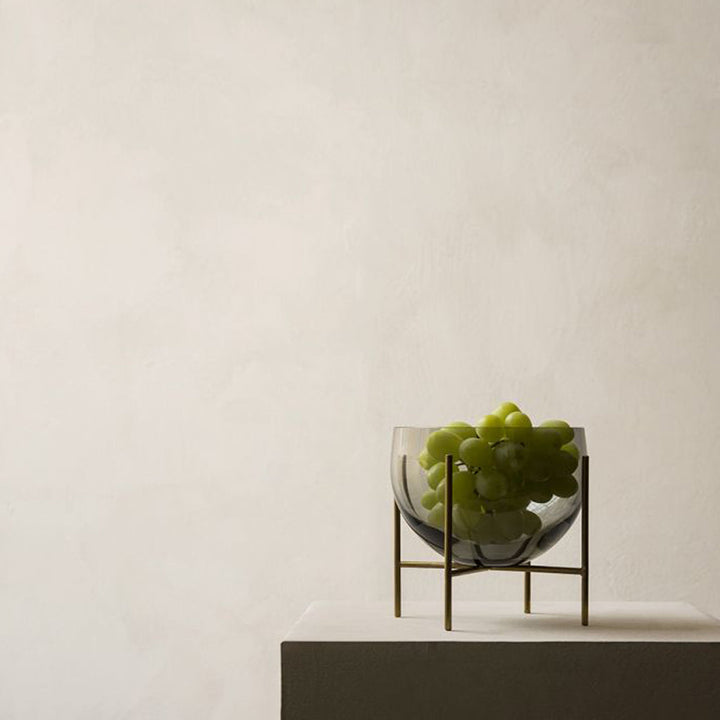 Elegant small bowl filled with green grapes sitting on a table.