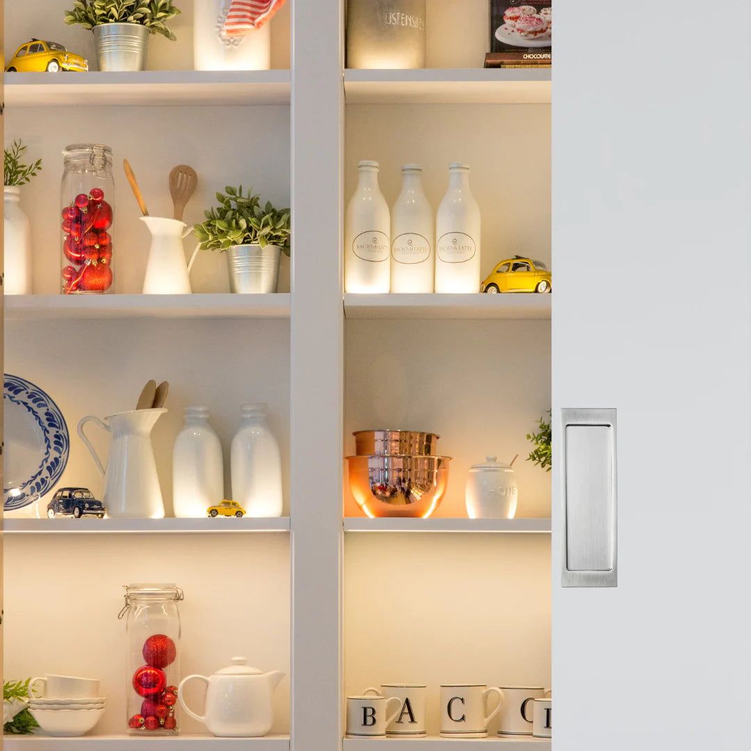 An AHI Explore Pocket Door Set Passage installed inside a white bookshelf filled with lots of different items.