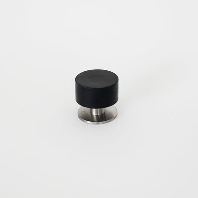 a black and silver knob on a white surface, replaced by the Extra Large Bumper Door Stop from AHI.