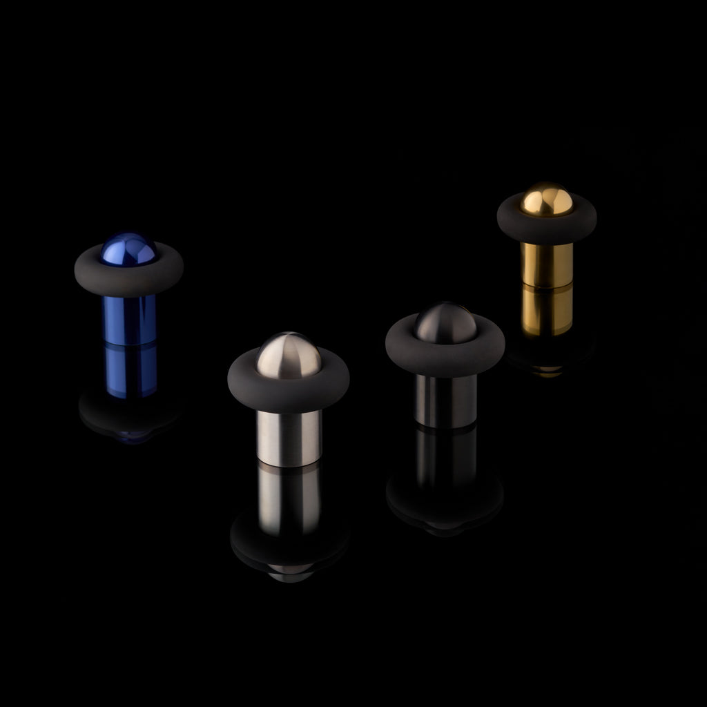 FAT Collection by Tom Dixon for d line. Door stops, all finishes, stood against a glossy black background.