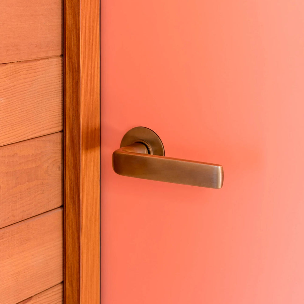 FSB 1267 lever and thumbturn on a coral-painted door at the Triesch Residence, showing the flat-grip form in situ.