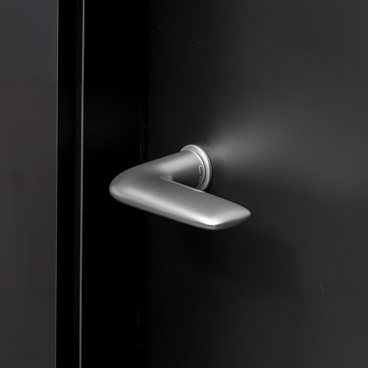 Satin FSB 1291 lever on a dark door, showing the short freehand curve of the grip.
