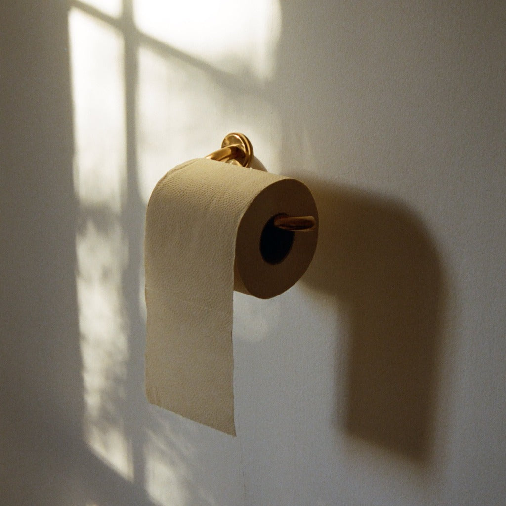 Brass Maha Alavi Fauna toilet paper holder with a roll.