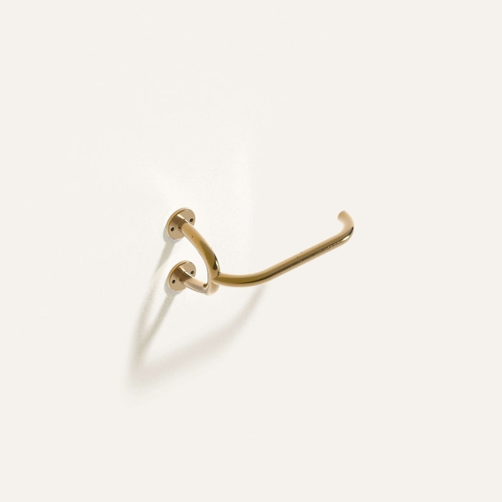 Fauna Toilet Roll Holder in polished brass installed on a white wall