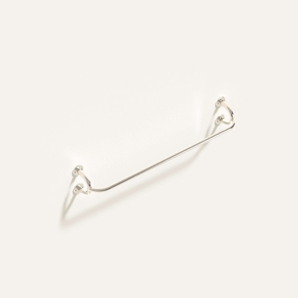 Fauna Towel Bar in polished stainless steel installed on a white wall showcasing it's gentle curves and clean lines.