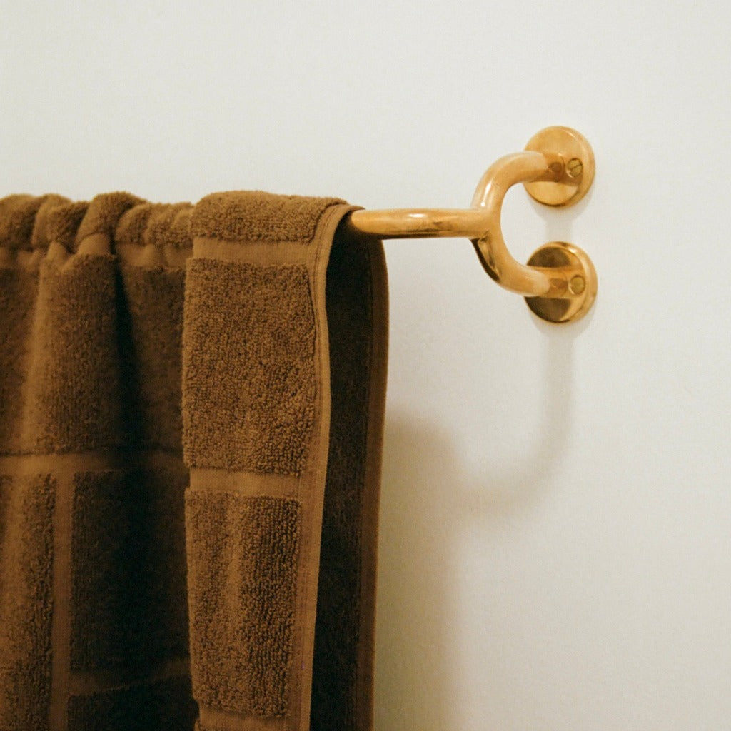 Brass Maha Alavi Fauna towel bar with brown towels.