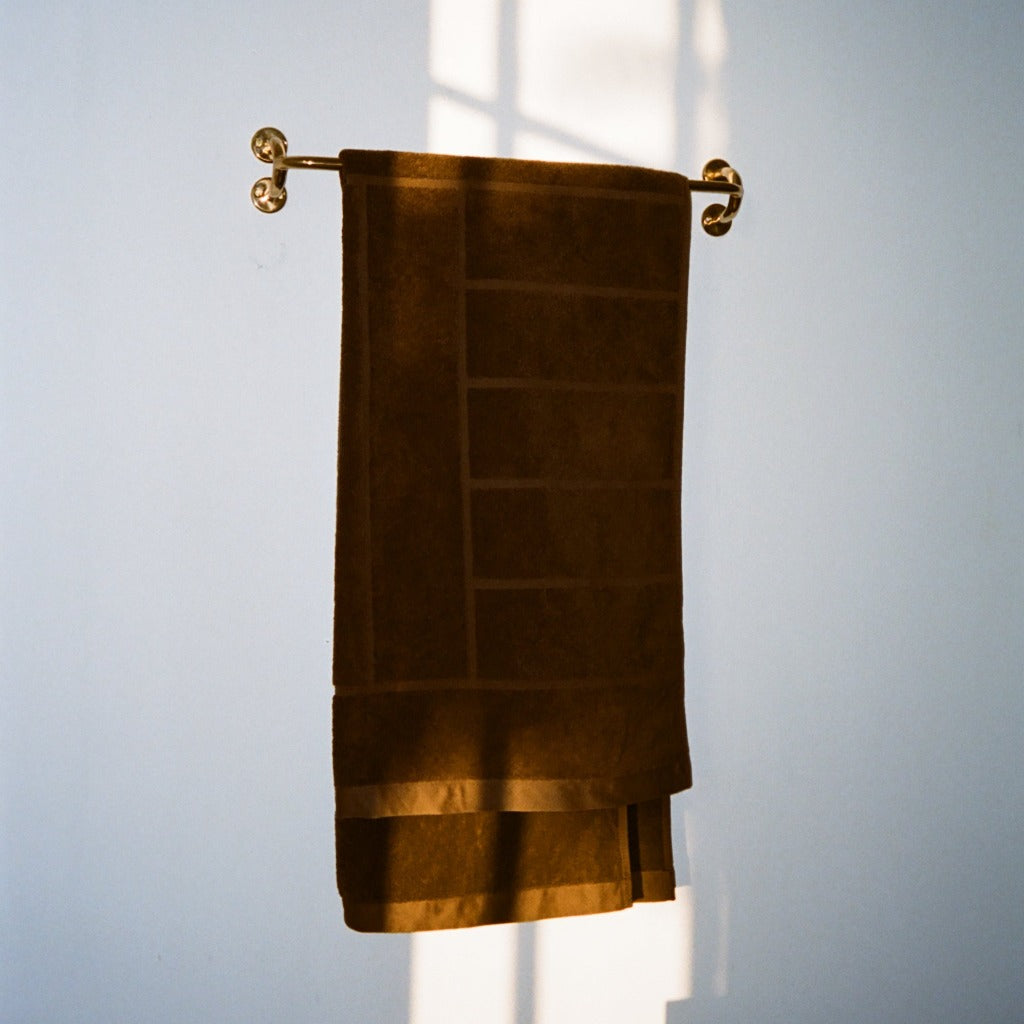 Brass Maha Alavi Fauna towel bar with a brown towel.