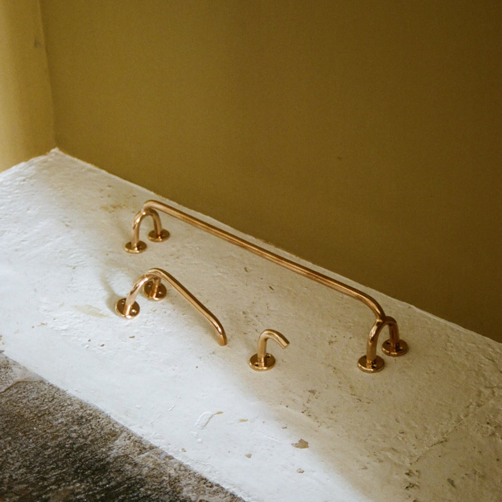 Brass Maha Alavi Fauna towel bar mounted low on a wall.